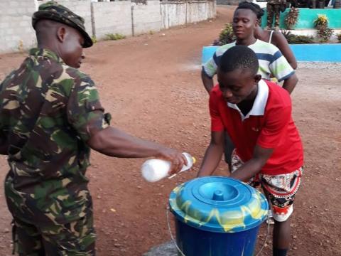 A military officer supervises a hand washing point at a border in eastern Sierra Leone A military officer supervises a hand washing point at a border in eastern Sierra Leone